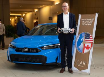 American Honda Zone Manager Josh Beckner holds the 2025 North American Car of the Year™ trophy next to the winning car, the 2025 Honda Civic Hybrid, in Detroit on January 10, 2025.
